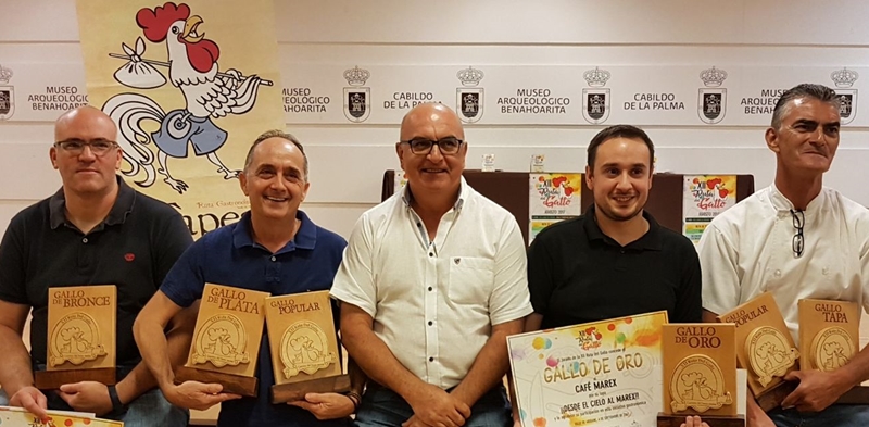 Sieger-Lokale der Ruta del Gallo. Die sommerliche Schlemmerreise auf der Ruta del Gallo durch Aridanetal ist vorbei und die Gäste haben wie immer die Sieger-Wirtshäuser gewählt: Der Gallo de Oro geht wieder einmal ans Café Marex in Los Llanos für die Tapa-Kombination aus Schweinefleisch, Ziegenkäse und Thunfisch. Der Hahn in Silber kräht 2017 im Restaurante Las Norias - den Juroren hatte eine Kreation mit gegrilltem Tintenfisch besonders gut geschmeckt. Der Gallo de Bronce wurde der Gastrobar Duende del Fuego in Los Llanos für eine kalte Maulbeersuppe verliehen. Den Preis für das beste "Tapa libre" errang in diesem Sommer die Tasca La Fuente in Los Llanos für ihr Ziegntapa mit Mandelsoße. Erstmals in der elfjährigen Geschichte der Ruta del Gallo ging ein Pokal zwecks Punktegleichheit an zwei Lokale: Den Gallo Popular teilen sich heuer das Restaurante Las Norias und die Tasca La Fuente.